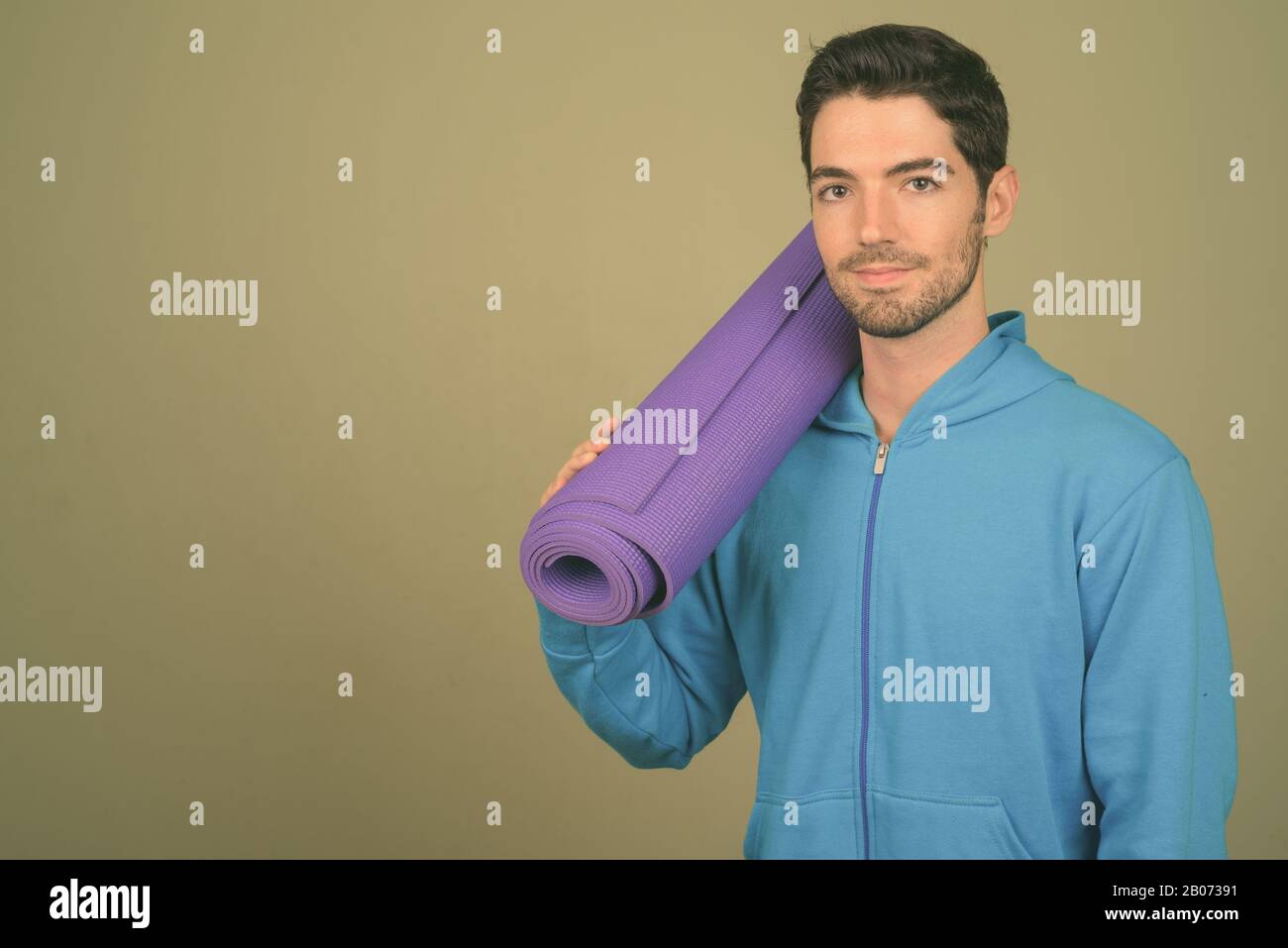 Junger gutaussehender Mann bereit für das Fitnessstudio vor farbigem Hintergrund Stockfoto