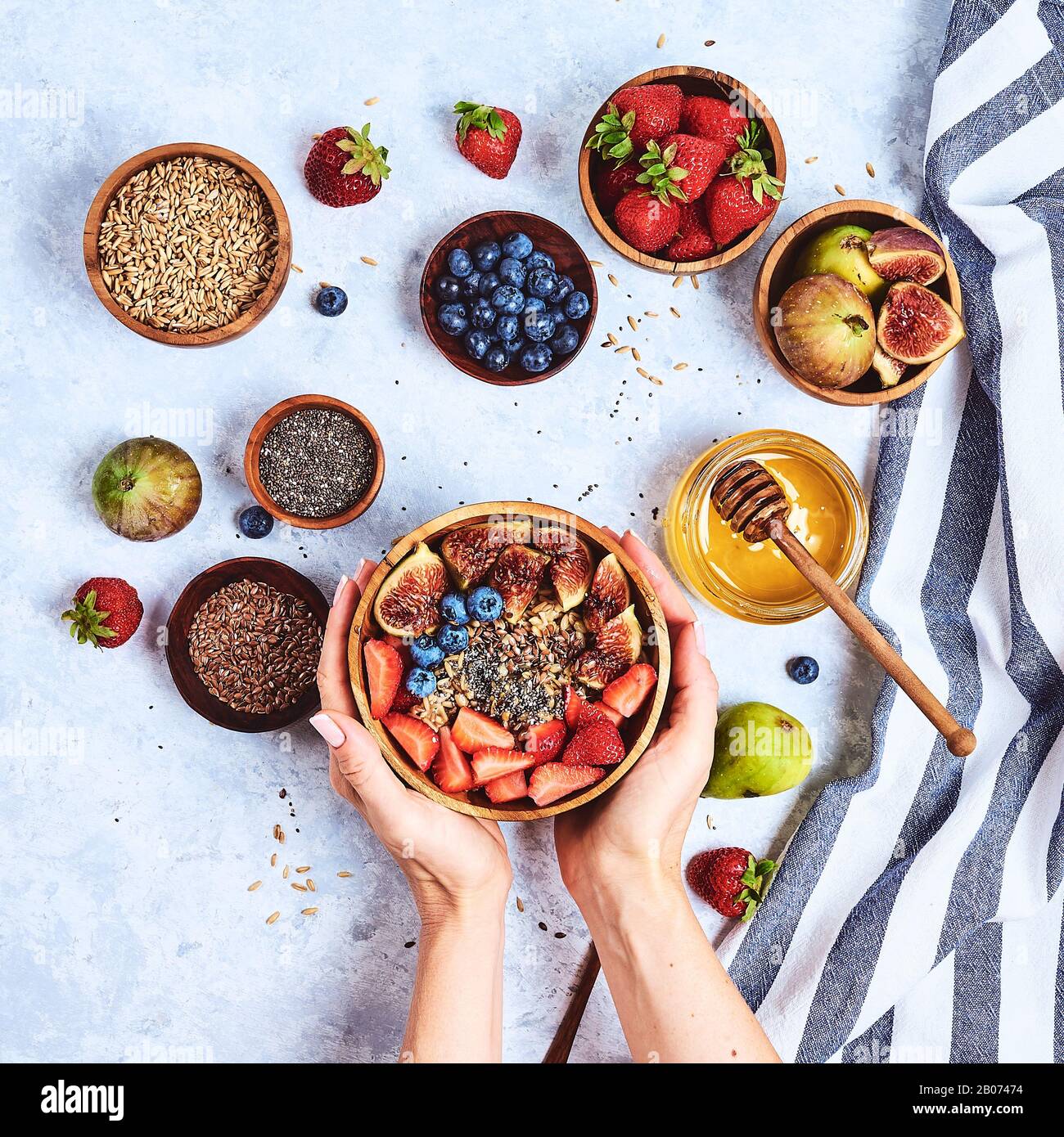 Ansicht von oben mit den Händen essen Porridge mit Honig, Nüsse, Blaubeeren auf weissem Holztisch selektiven Fokus, verschwommenen Hintergrund Guten Morgen - gesunde b Stockfoto