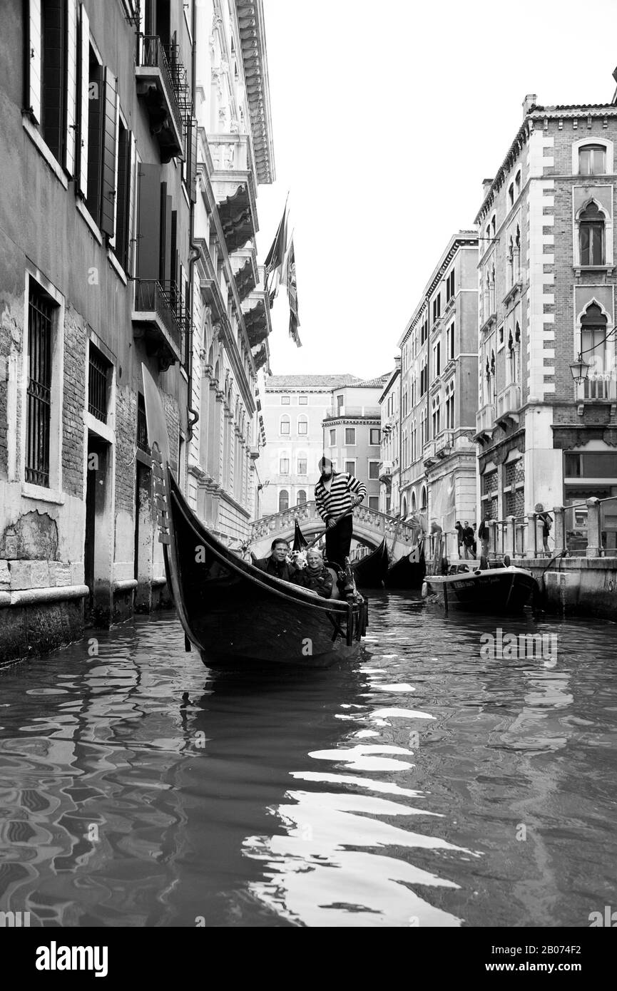 Stadt Venedig, Italien, Europa. Schwarz-Weiß-Bild von Gondola mit Touristen und Gondolierin am schmalen Kanal Venedig Stockfoto