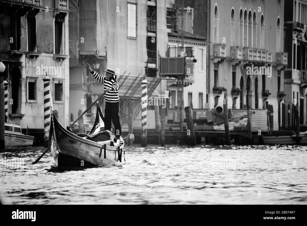 Stadt Venedig, Italien, Europa. Schwarz-Weiß-Bild von Gondolier in traditionellem Kleid, geweht von Gondola am Canal Grande Stockfoto