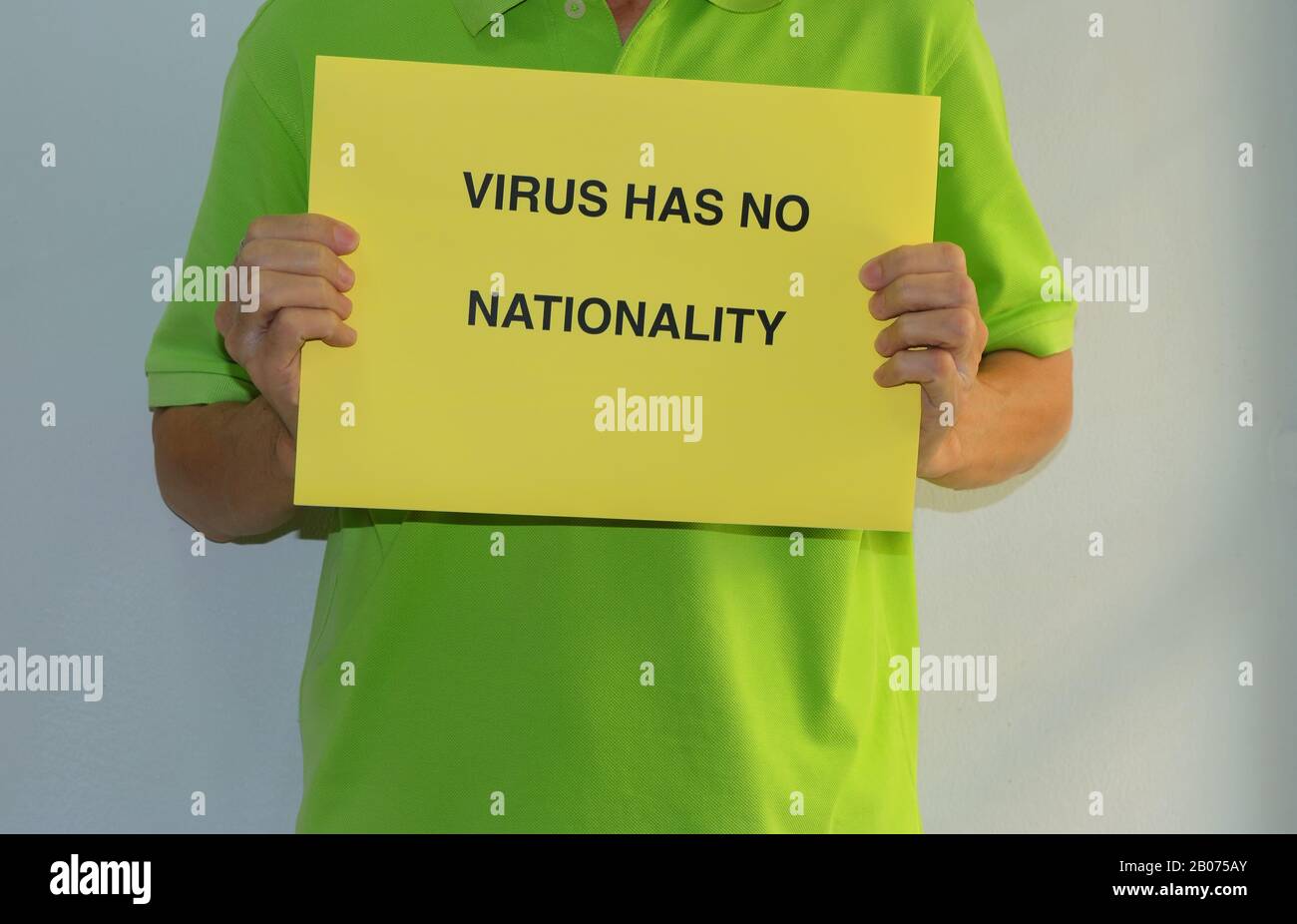 Ein asiatisches Schild mit gelbem Papier enthält eine mit Großbuchstaben gedruckte Nachricht VIRUS HAT KEINE NATIONALITÄT, Anti-Fremdenfeindlichkeit-Konzept Stockfoto