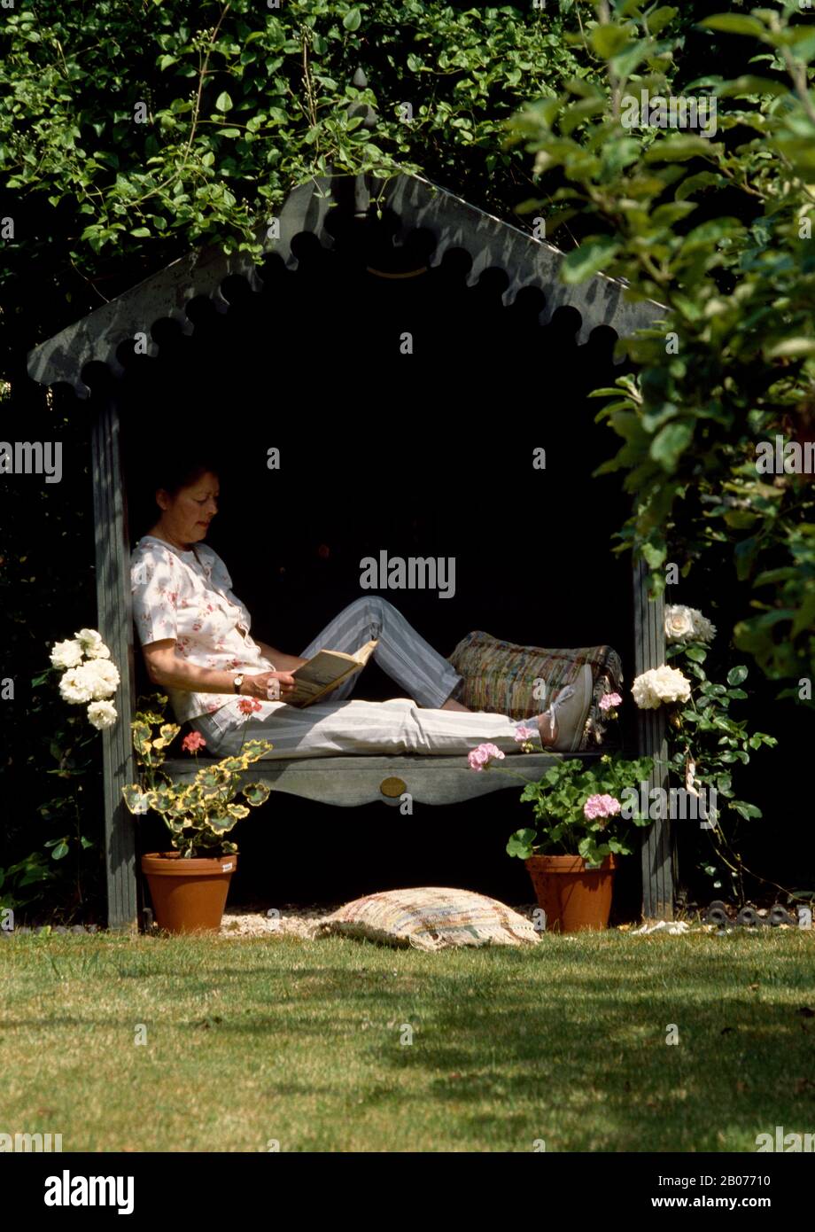 Frau liest nur in DER SOMMERGARDENFOR-REDAKTION an einem schattigen Ort Stockfoto