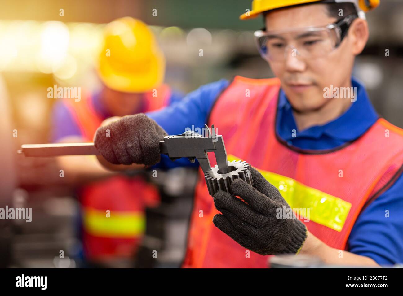 Techniker, der den Vernier Caliper verwendet, um die Getriebegröße auf Genauigkeit zu prüfen. Präzise Qualitätskontrolle des Serviceteils im Werk. Stockfoto