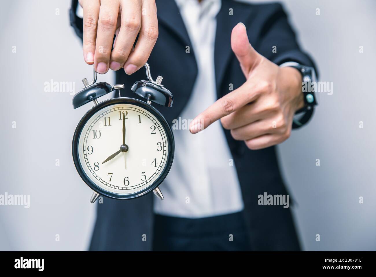 Geschäftsleute zeigen mit dem Finger auf Uhrzeiten um 8 Uhr, erinnern sich an die Zeit, etwas zu tun oder ein Timing-Hinweistor zu machen Stockfoto