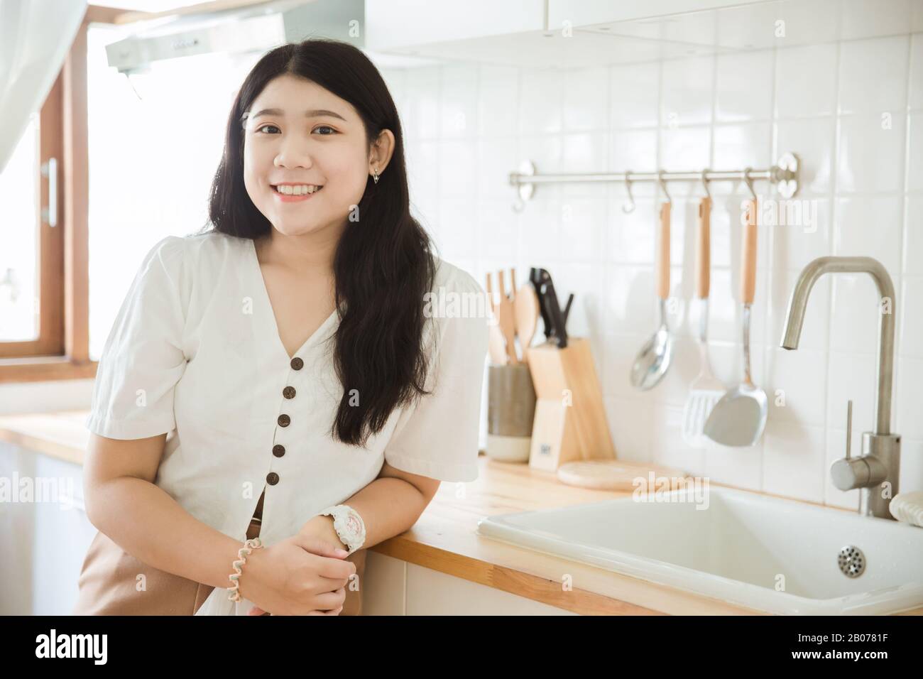 Süßes asiatisches Mädchen, das in der Küche lächelt, für junge Hausfrau aus Asien, die gerne kocht. Stockfoto