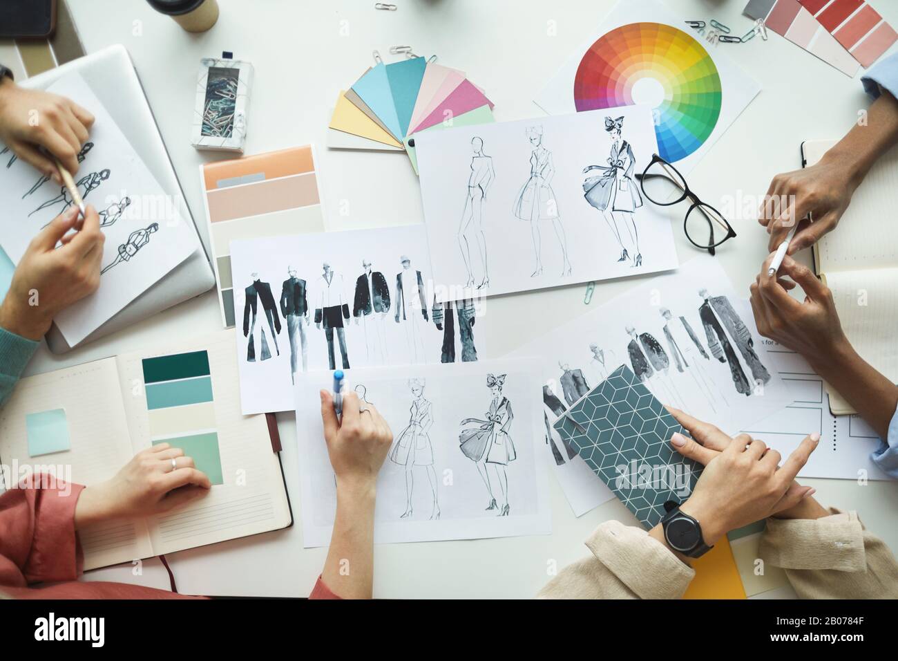 Ein Team von Designern, die mit Skizzen von Kleidung und Farbpalette arbeiten und die Sammlung von Planungen im Team planen Stockfoto