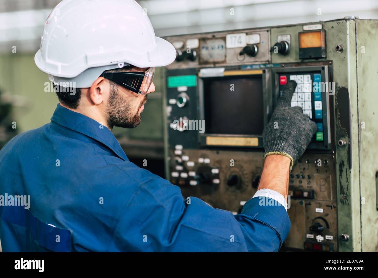 Der Arbeiter der Fabrik betreibt die Maschine, die Arbeitsbranche mit hoher Qualifikation und Sicherheitskleidung. Stockfoto