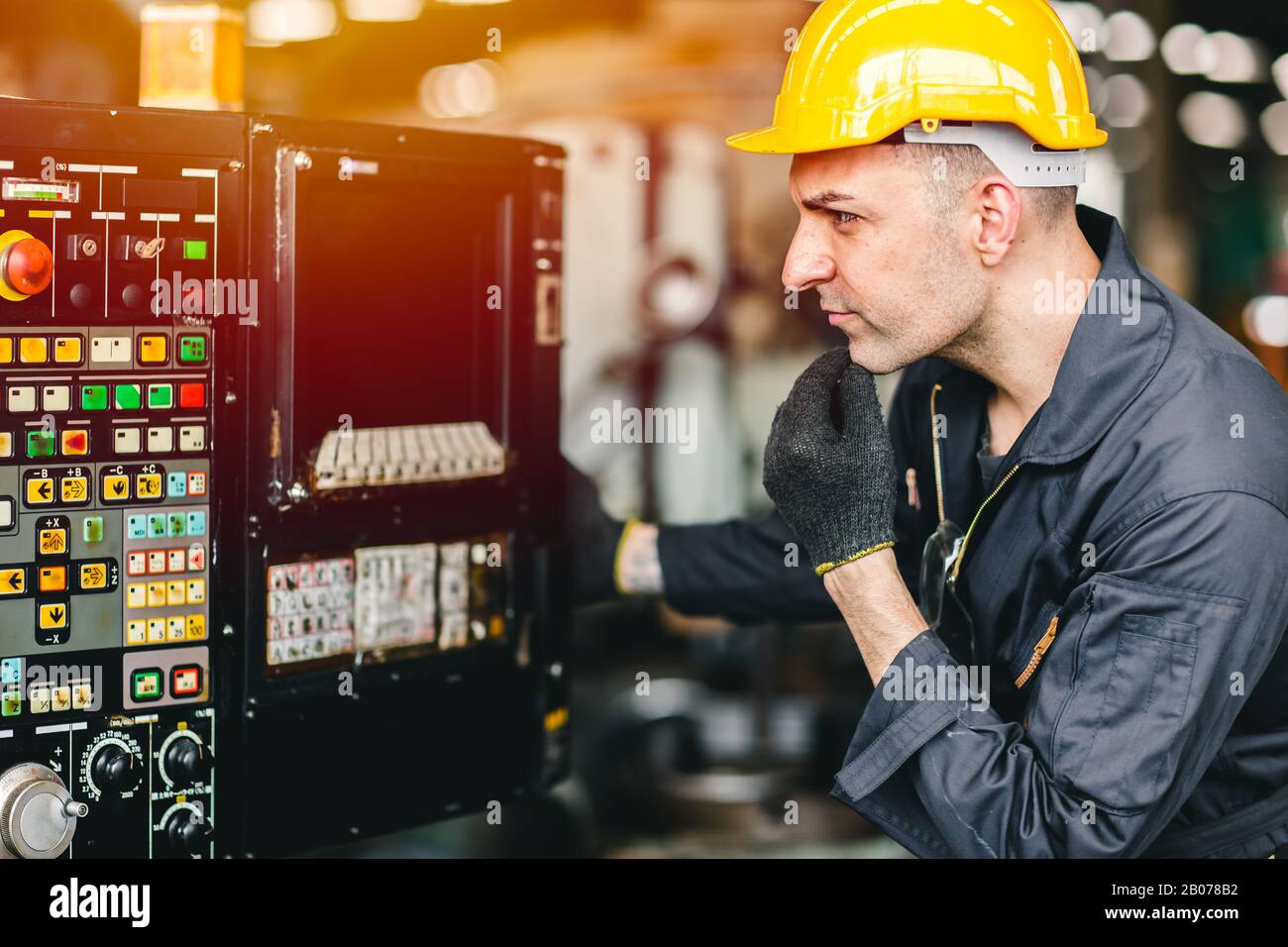 Der Arbeiter der Fabrik betreibt die Maschine, die Arbeitsbranche mit hoher Qualifikation und Sicherheitskleidung. Stockfoto