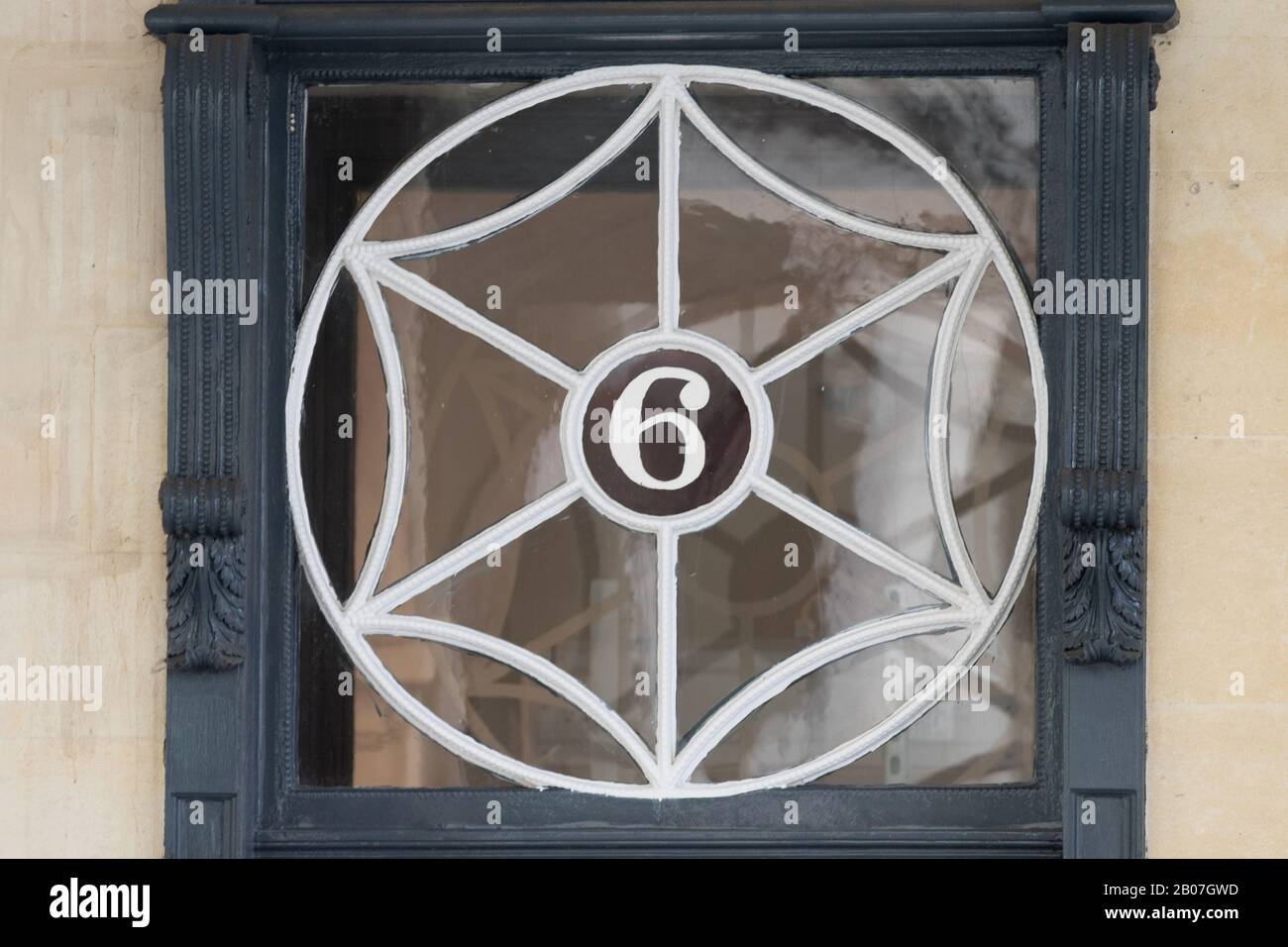Webförmiges Glasfenster mit der Nummer sechs über einer Ladentür in der Stadt Bath, Somerset, Großbritannien Stockfoto