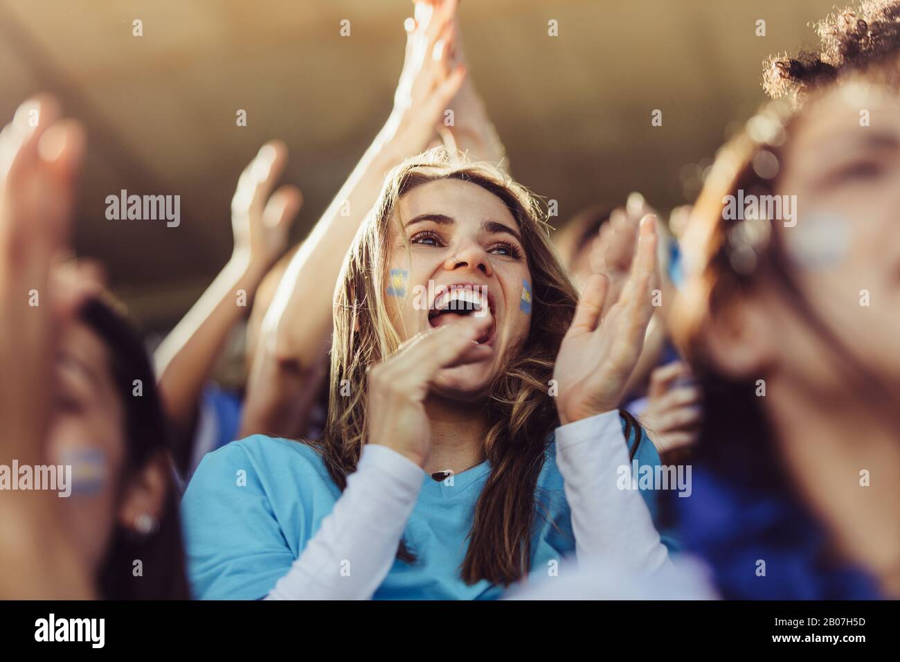 Begeisterte Fans in der Sportmenge feiern auf Teamerfolg. Gruppe argentinischer Fußballfans jubelt in Ständen. Stockfoto