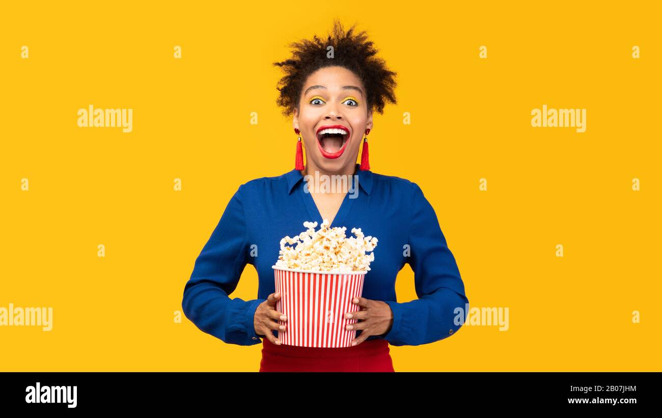 Tausendjähriges schwarzes Mädchen mit Popcorn, das Popcorn schüttelt Stockfoto