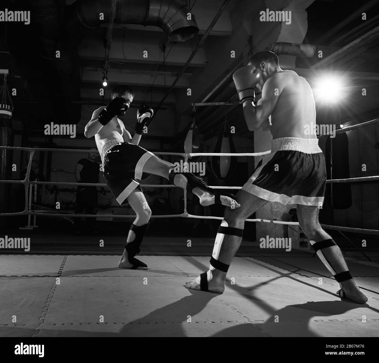 Zwei aggressive Boxer trainieren Kickboxen im Ring beim Sportclub. Schwarz-Weiß-Bild Stockfoto