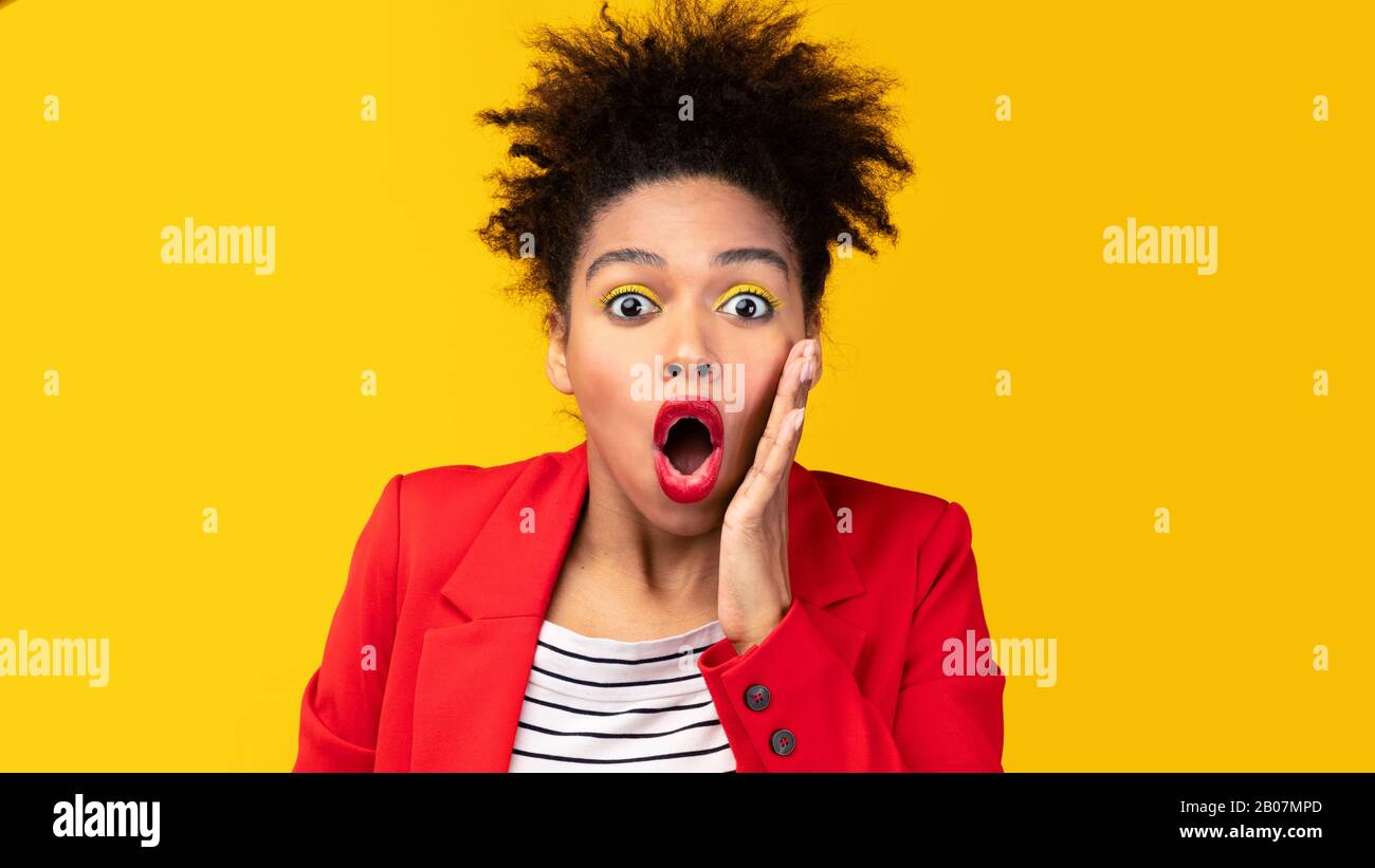 Überraschte afro-Frau schreit und berührt ihre Wange Stockfoto