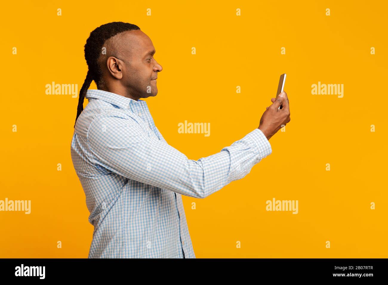 Mann im mittleren Alter, der sein Gesicht auf dem Handy abtastet Stockfoto