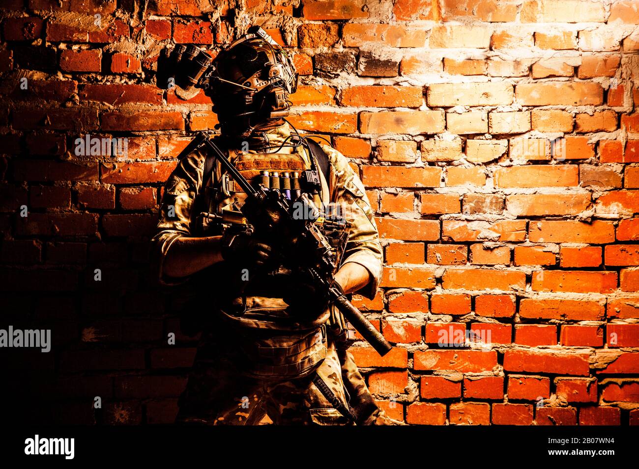 Spezialeinsatzkräfte Soldaten, Mannschaftskämpfer der Terrorismusbekämpfung mit Nachtsichtgerät auf Helm und Dienstgewehr, mit niedrigem Schlüssel in der Halle geschossene Ziegelwand Stockfoto