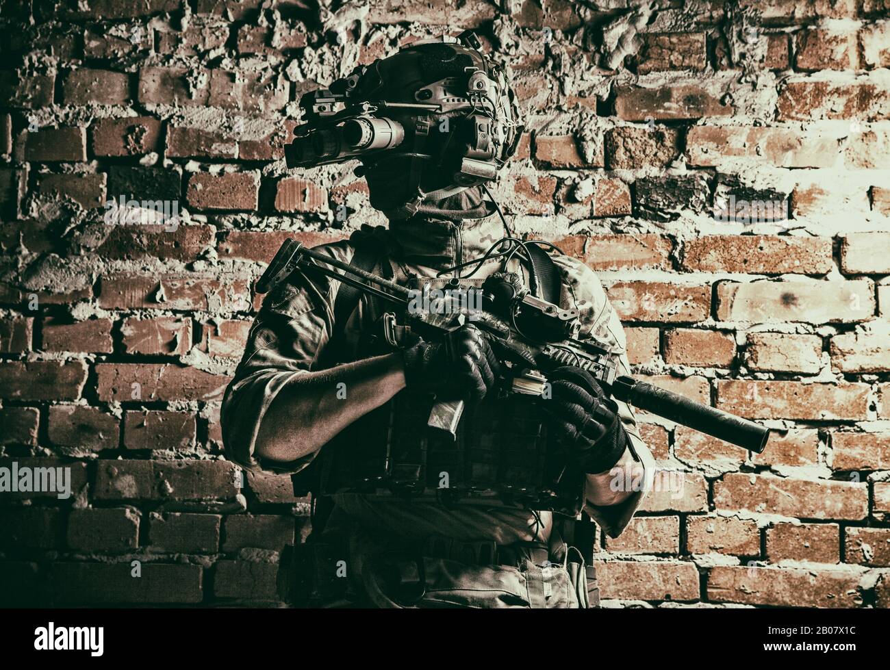 Armee Spezialeinsatzkräfte taktischer Gruppenjäger in der cqb-Mission, mit Funk-Headset, Blick durch die Nachtsicht mit vier Objektiven, Wärmebildgerät auf Helm, bewaffnete kleine Untermaschinenpistole mit Schalldämpfer Stockfoto