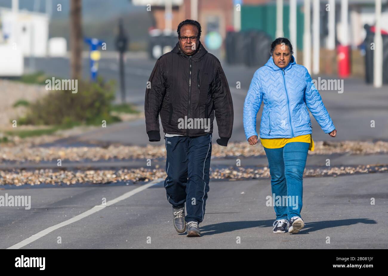 Asiatisches (möglicherweise indisches) Paar Menschen, die an einem kalten Tag auf einer Promenade in England, Großbritannien, zusammen spazieren und Mäntel tragen. Stockfoto