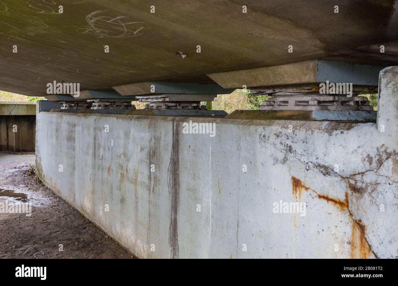 Stützlager auf einer Betonstraßenbrücke, die vermutlich Spannungsrisse im Beton zeigen. Stützpolster der Lager überbrücken. Stockfoto