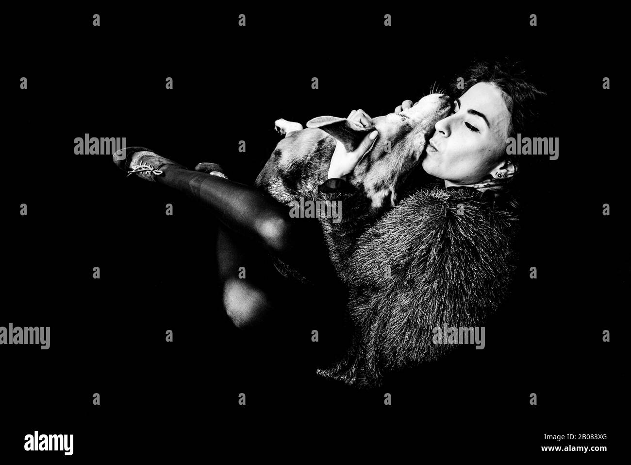 Kontrastreiches Schwarz-Weiß-Bild der jungen Frau, die ihren Tagle Hund knudelt und liebevoll küsst Stockfoto