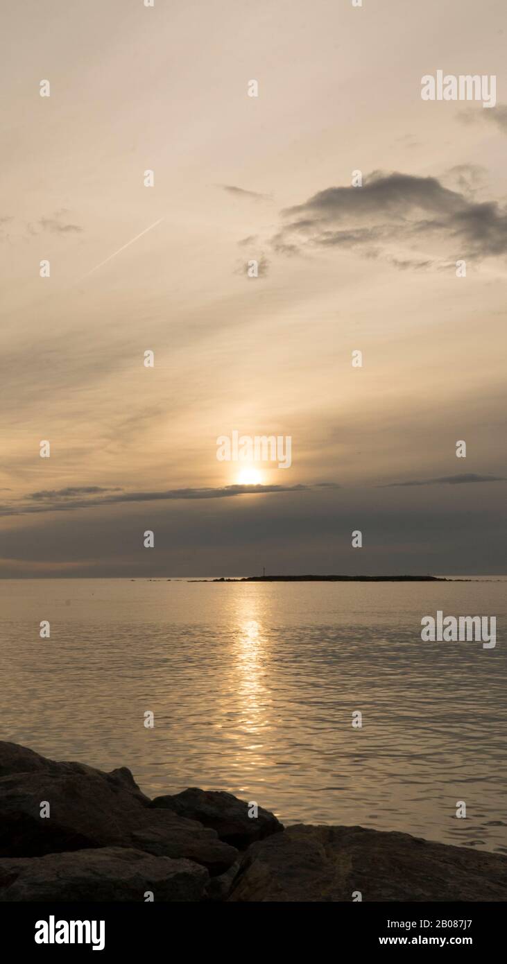 Emotionaler Schuss einer Bucht bei Sonnenaufgang oder Sonnenuntergang bei Hintergrundbeleuchtung mit sehr bewölktem Himmel Stockfoto