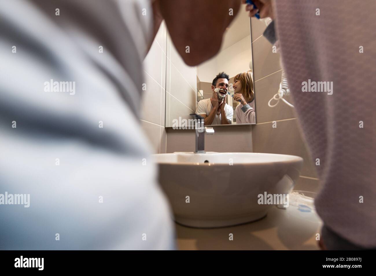 Morgens ein paar Routine. Mann und Frau teilen sich das Bad. Rasierbart und Zähne putzen Stockfoto