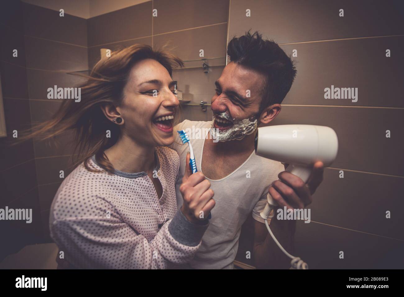 Morgens ein paar Routine. Mann und Frau teilen sich das Bad. Rasierbart und Zähne putzen. Beginnen Sie den Tag in einer tollen Stimmung Stockfoto