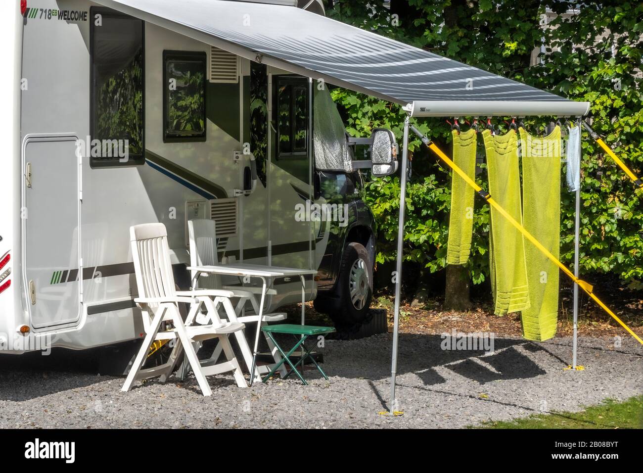 Drei grüne Handtücher hängen in der warmen Sonne, vom Sonnenschein/Sonnenschutz eines Wohnwagens, auf einem Zeltplatz ohne Leute herum zum Trocknen. Engand, Großbritannien. Stockfoto