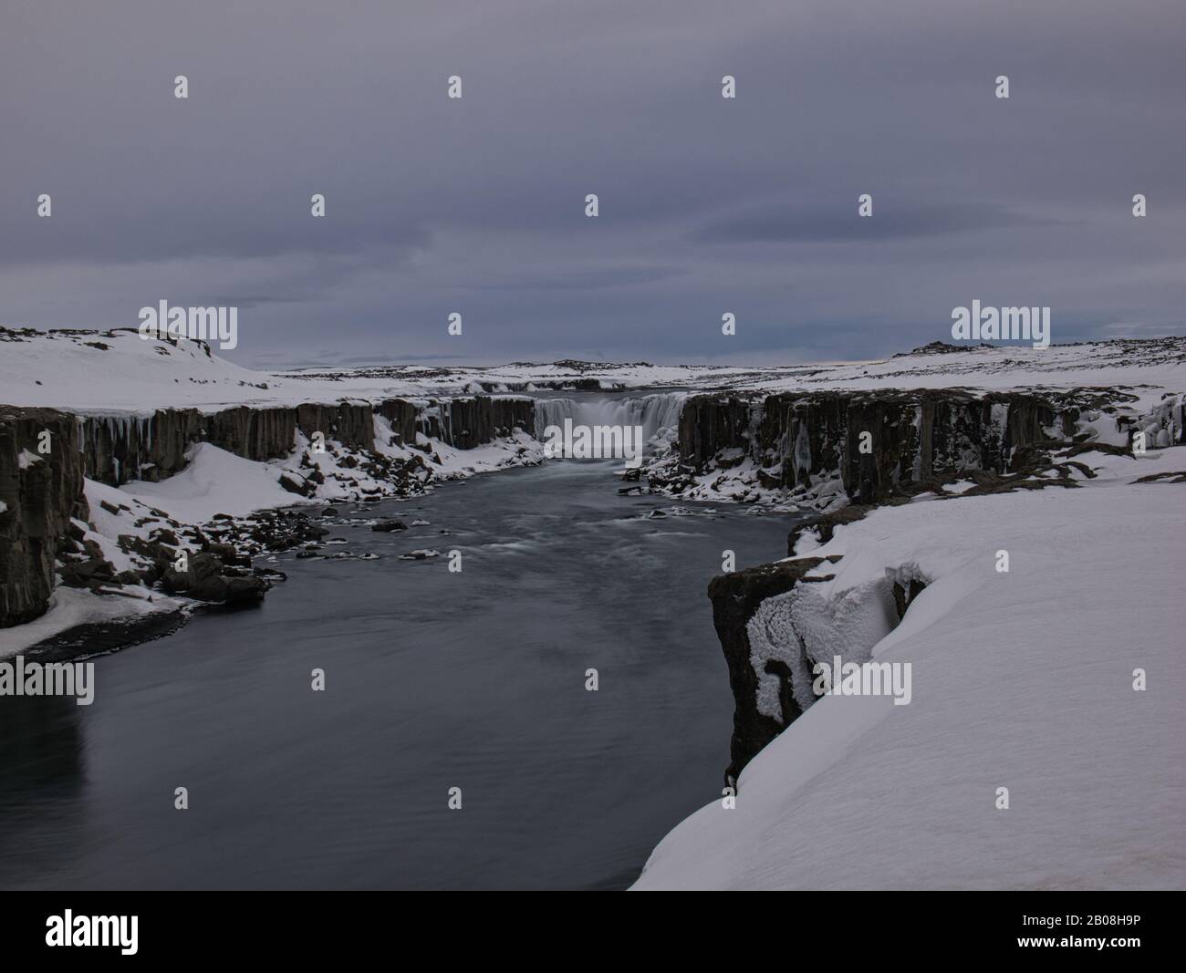 Eine lange Zeit andauende Exposition des Dettifoss Wasserfalls mit Schnee Stockfoto