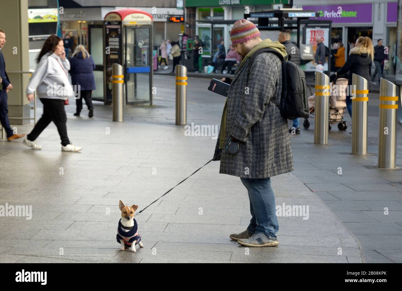 Mann mit kleinem Hund an der Leine, wartend. Stockfoto