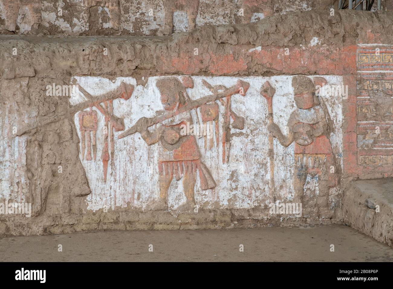 Bemalte und geschnitzte Reliefe von siegreichen Kriegern aus der präinkanisch-mochicanischen Kultur an den adobe-wänden der Huaca de la Luna bei Trujillo, Peru Stockfoto