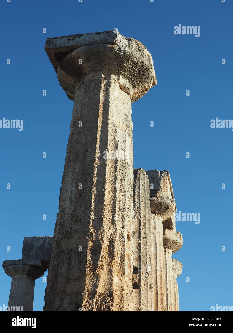 Dorische Säulen des Archaischen Tempels zu Apollo in Korinth, Peloponnes, Griechenland gegen einen blauen Himmel. Jahrhundert v. Chr. erbaut. Stockfoto