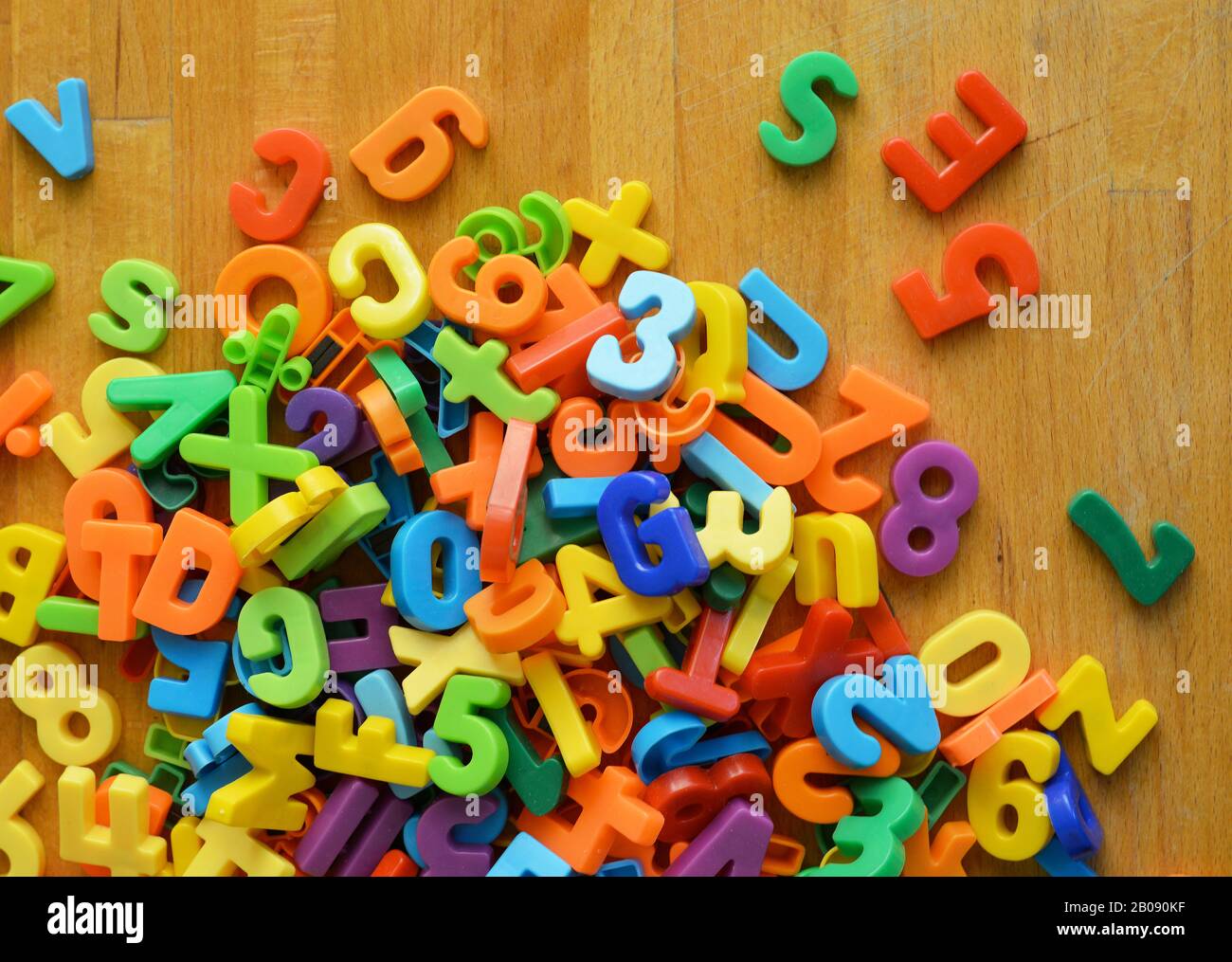 Eine chaotische Gruppe von bunten Buchstaben und Zahlen auf einem Holzboden Stockfoto