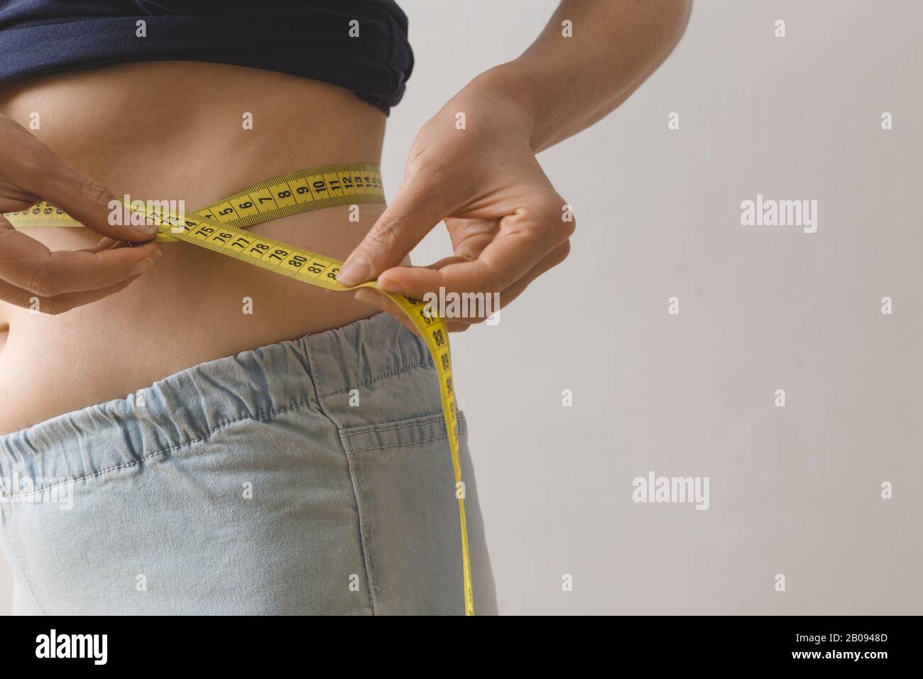 Eine junge Frau misst ihre Taille mit einem Maßband. Das Konzept des Gewichtsverlustes. Stockfoto