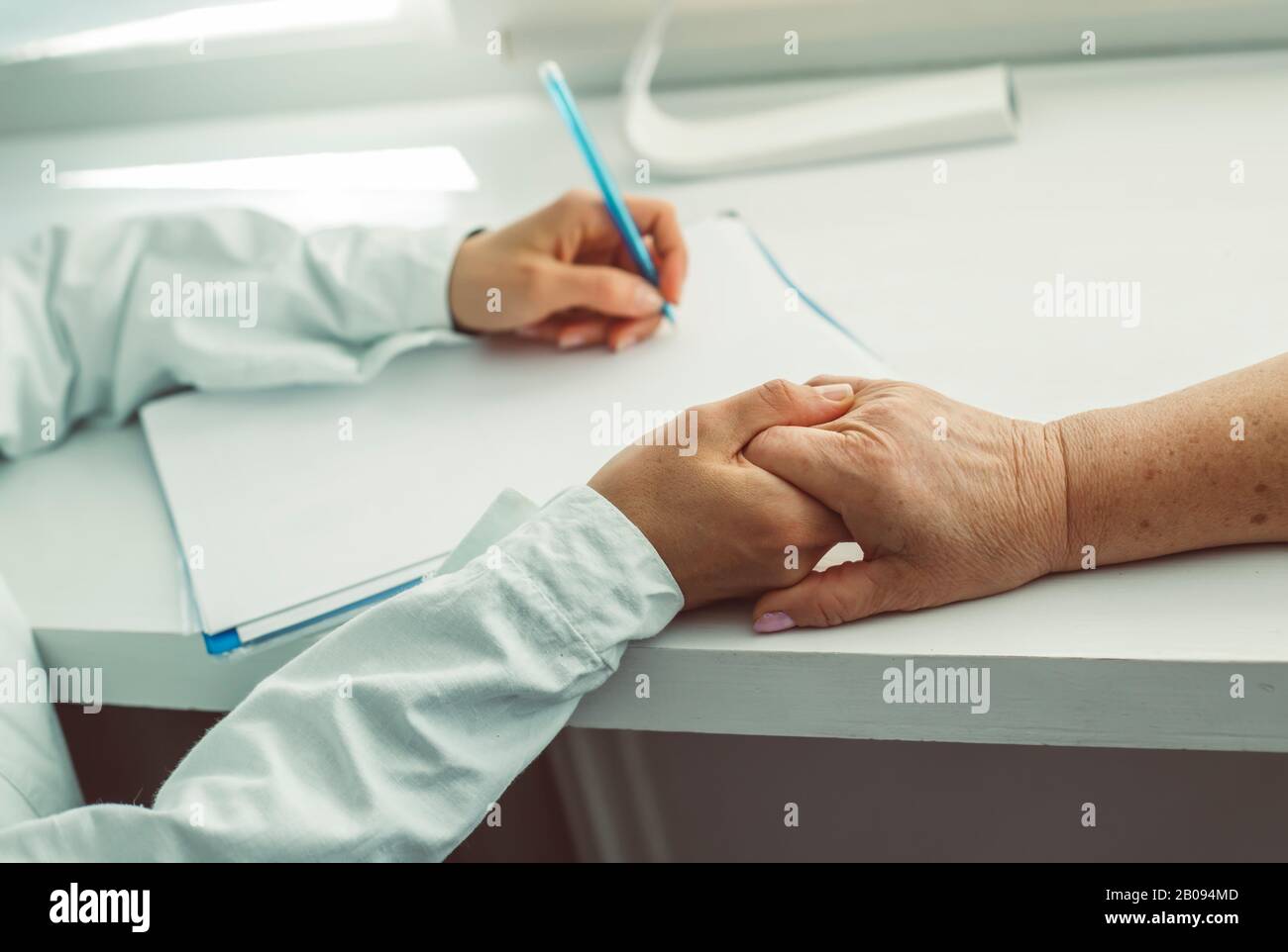 Der Arzt hält die Hand einer älteren Frau. Eine Krankenschwester unterstützt eine alte Patientin. Stockfoto Der Arzt hält die Hand einer älteren Frau. Eine Krankenschwester unterstützt eine alte Patientin. Stockfoto
