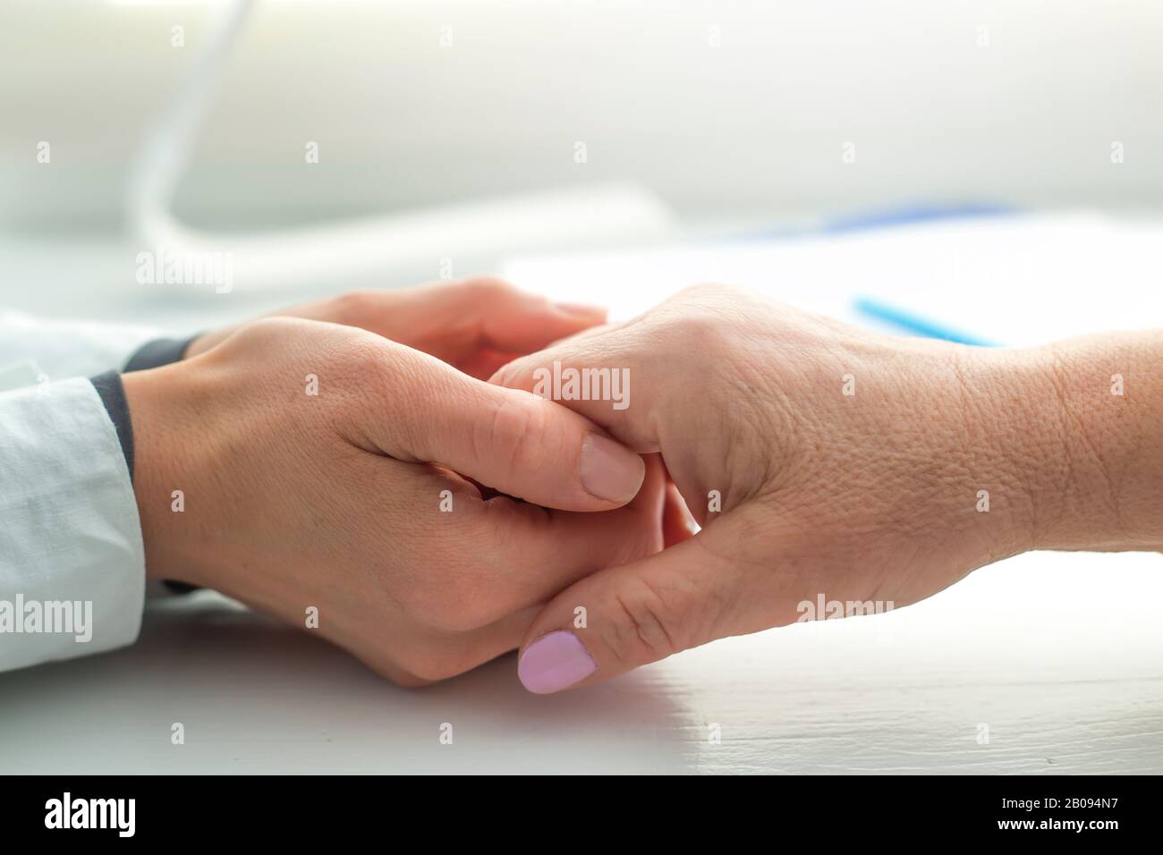 Der Arzt hält die Hand einer älteren Frau. Eine Krankenschwester unterstützt eine alte Patientin. Stockfoto