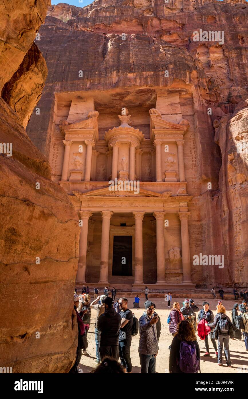 Petra, JORDANIEN - 30. JANUAR 2020: Viele Touristen genießen sonnigen Tag im berühmten Tempel El-Khazneh, von der Schlucht Al-Siq aus gesehen, die in Felswänden gehauen ist Petra Komplex und Touristenattraktion, Haschemite Königreich Jordanien Stockfoto