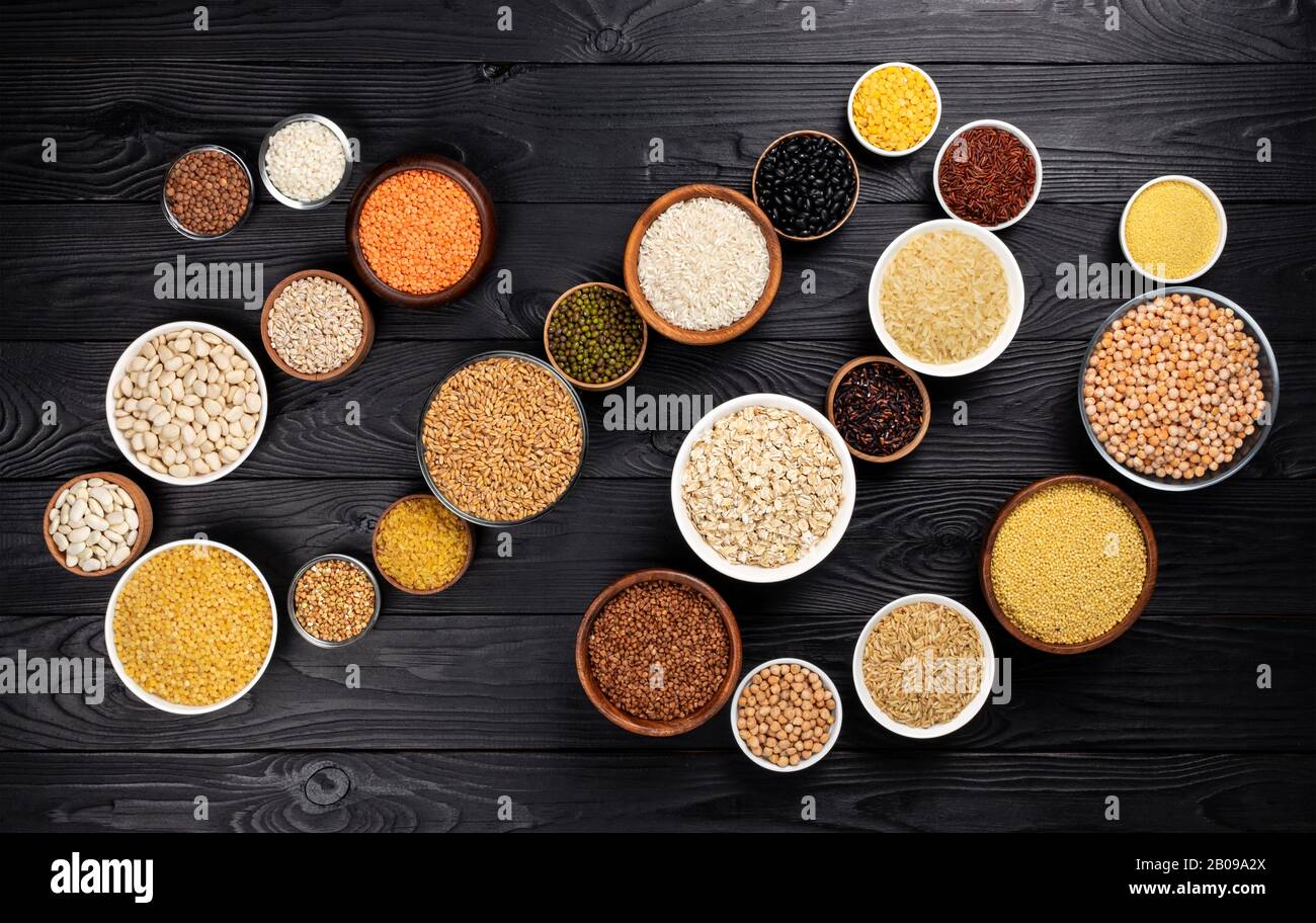 Getreide, Körner, Samen und Grütze schwarze hölzerne Hintergrund Stockfoto