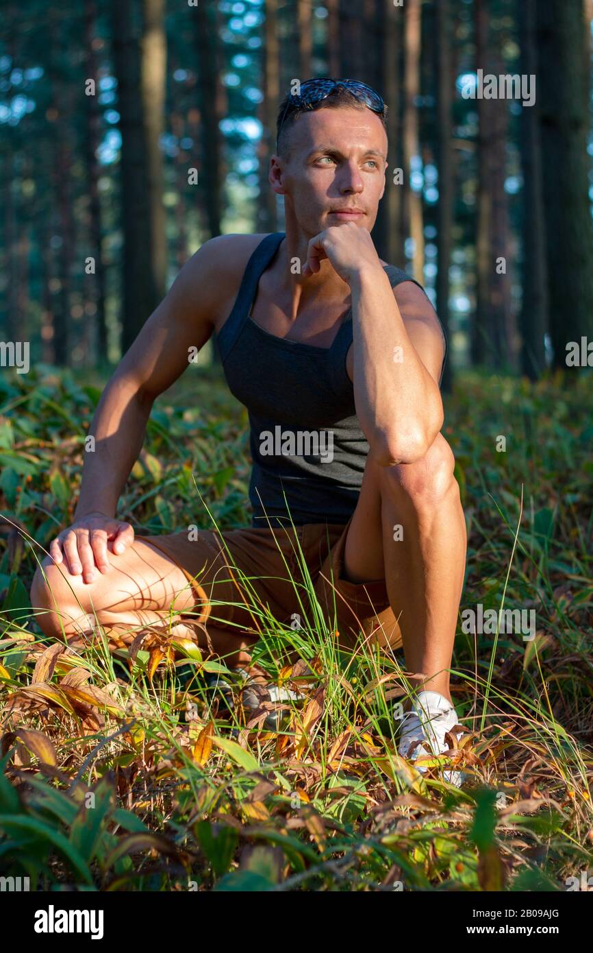 Ein sportlicher Mann im Wald, entspannend bei Sonnenuntergang. Stockfoto