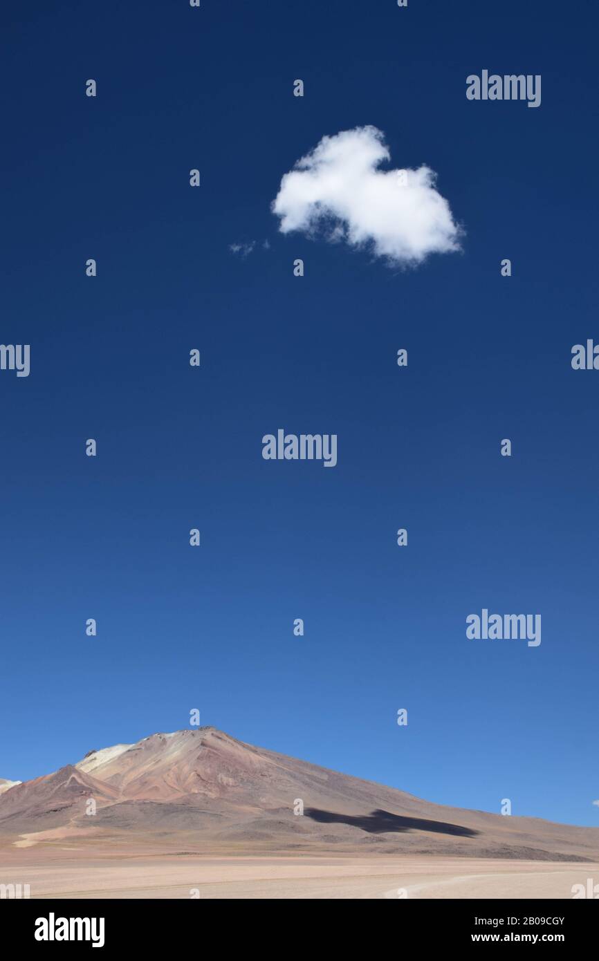 Eine einzige Wolke im klaren blauen Himmel, die auf einer Bergseite in der Landschaft des bolivianischen Hochlandes Schatten erzeugt. In der Nähe der wüste salvador dali in Th Stockfoto