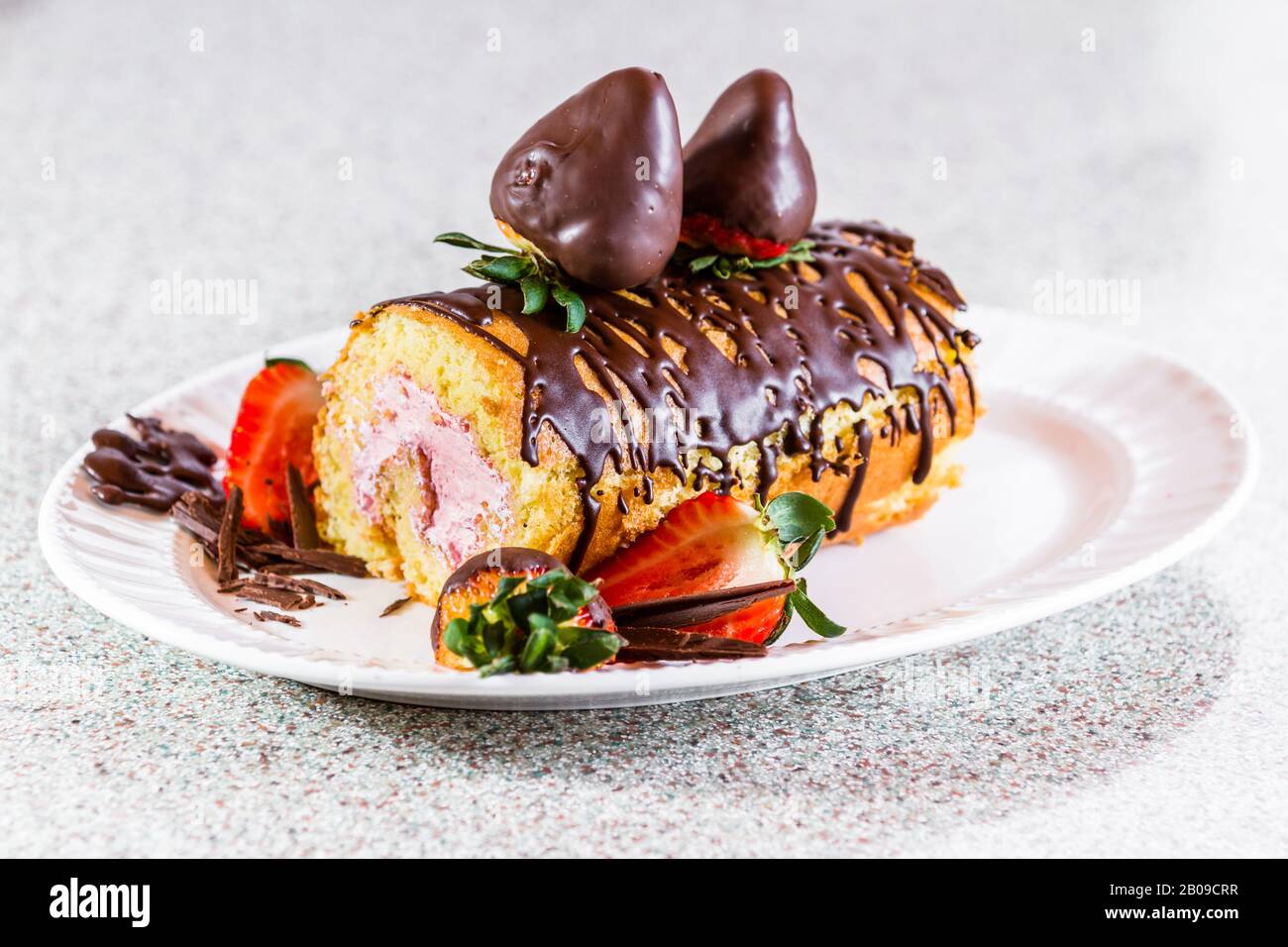 Nahaufnahme einer Vanillekuchenrolle mit frischer Erdbeermaus und mit schokoladenüberzogenen Erdbeeren garniert Stockfoto