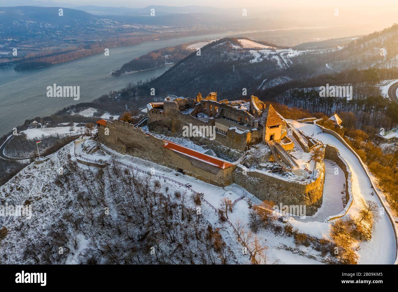 Visegrad, Ungarn - Blick Auf die schöne verschneite Hochburg von Visegrad bei Sonnenaufgang mit Dunakanyar im Hintergrund. Wintermorgen Stockfoto