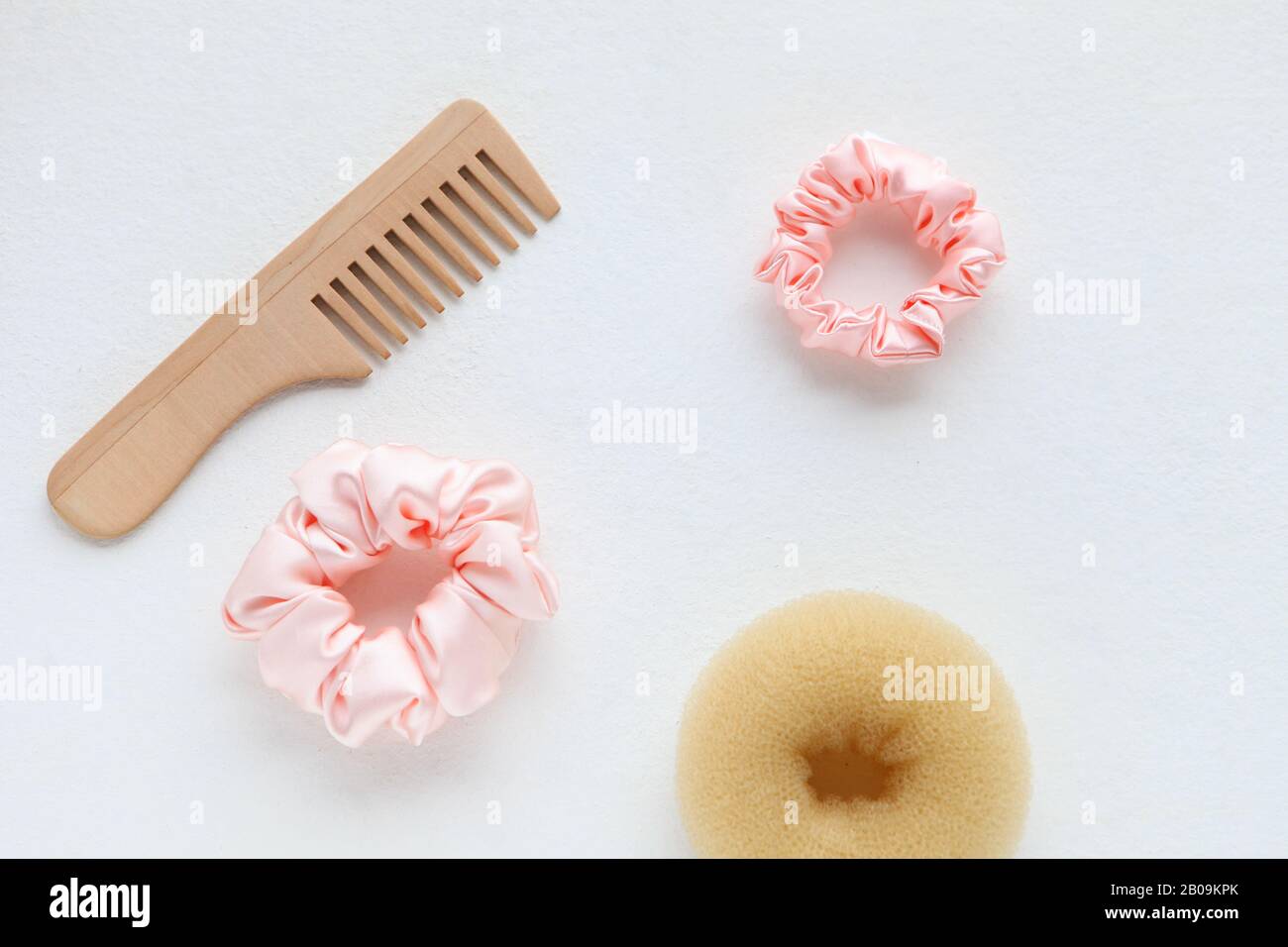 Haarbürste aus Holz, Barrette und Pink Scrunchy isoliert auf Weiß. Flat Lay Frisierwerkzeuge und Accessoires Color Hair Scrunchies, Elastisches Haar Stockfoto