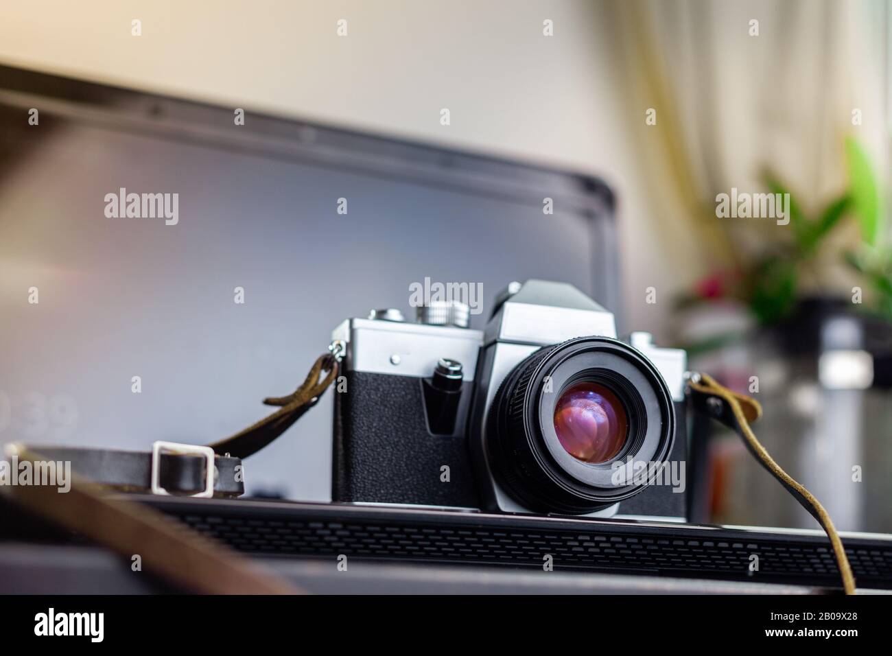 Analoge Vintage-Filmkamera auf einem Laptop auf einem Holztisch Stockfoto