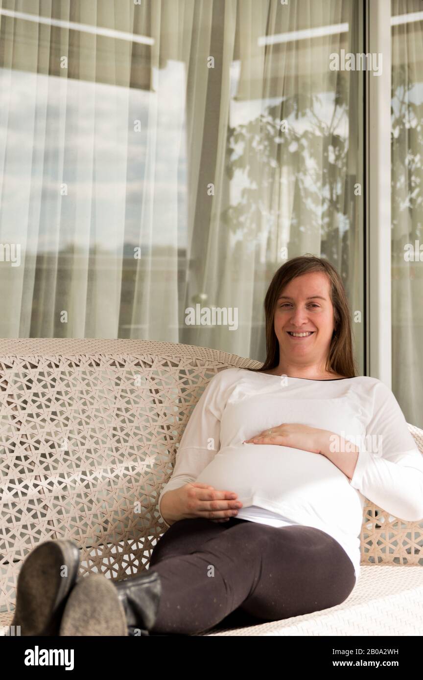 Schwangere 30-jährige Frau posiert in einem Sessel in einer Galerie Stockfoto