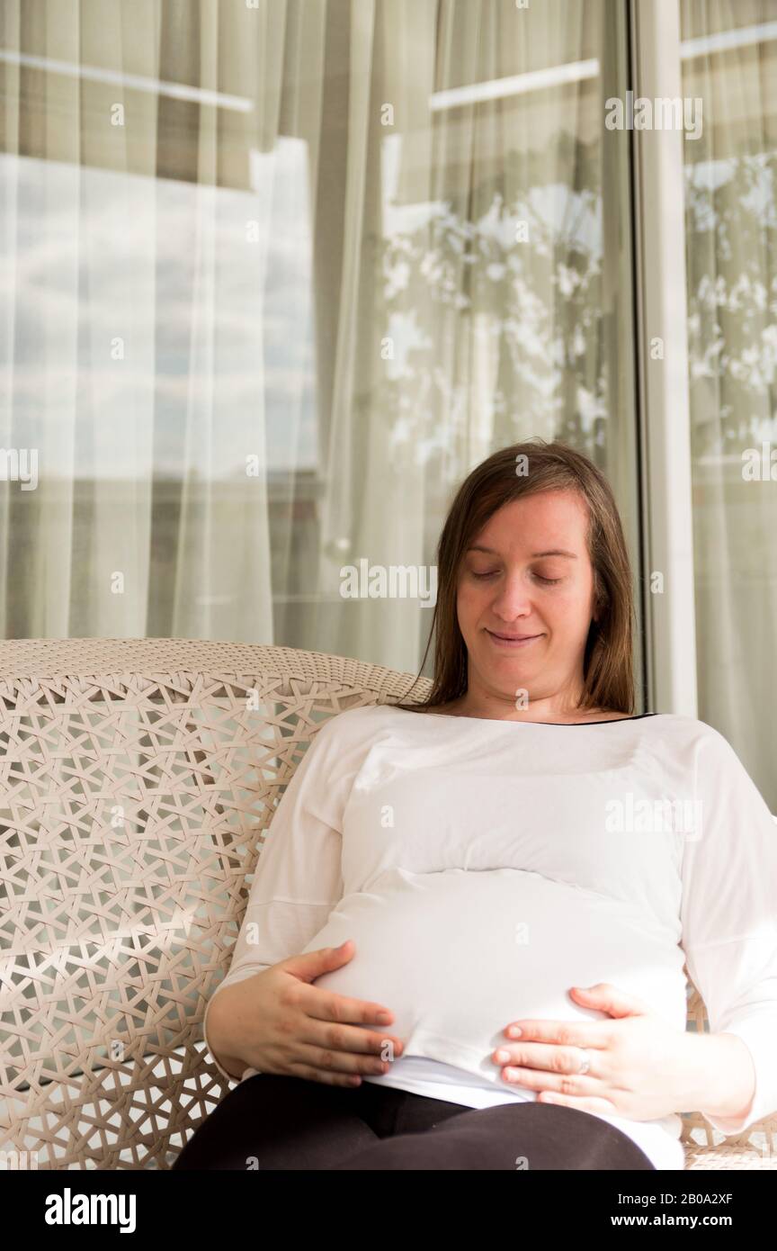 Schwangere 30-jährige Frau posiert in einem Sessel in einer Galerie Stockfoto