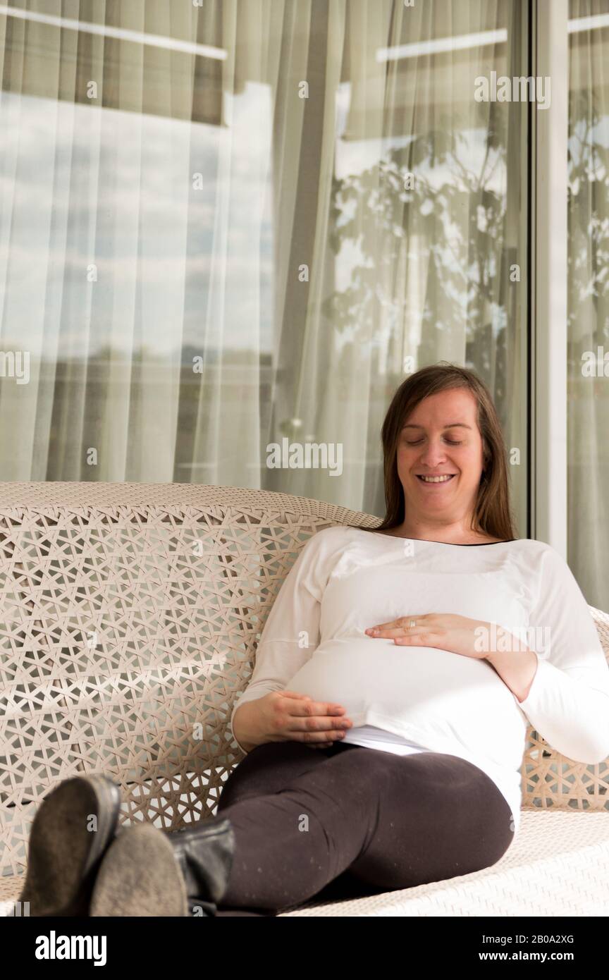 Schwangere 30-jährige Frau posiert in einem Sessel in einer Galerie Stockfoto