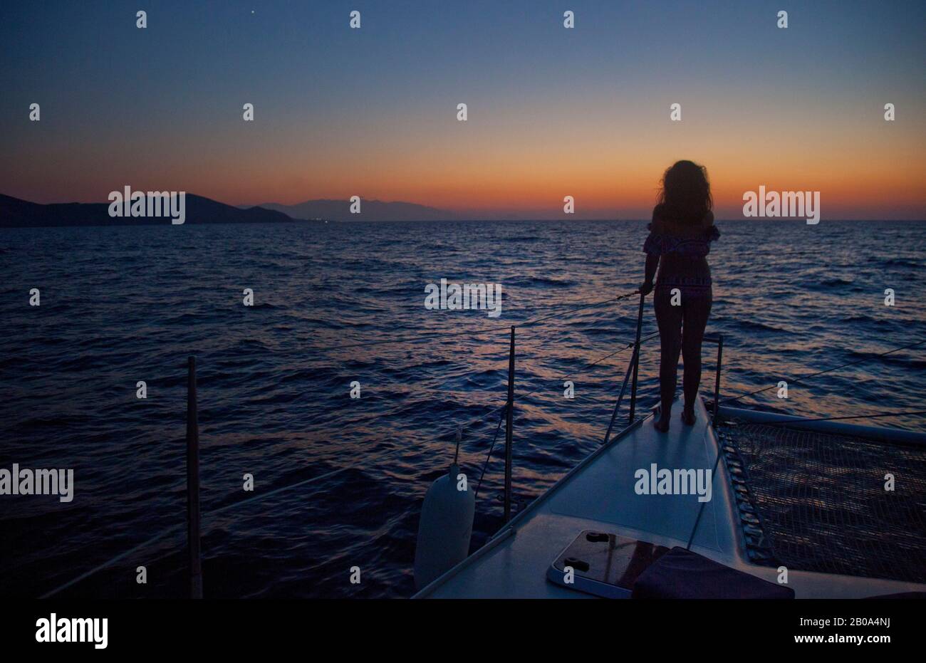 Ein Teenager-Mädchen (Modell veröffentlicht) beobachtet den Sonnenuntergang, vom Bug einer Yacht, auf Crete an der Nordküste zwischen Bali und Panoramos. Stockfoto