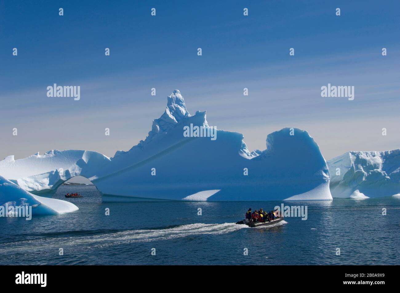 ANTARKTIS, ANTARKTISCHE HALBINSEL, EISBERG MIT BOGEN AN DER PALMER STATION (US-FORSCHUNGSSTATION), TOURISTEN IN ZODIACS Stockfoto