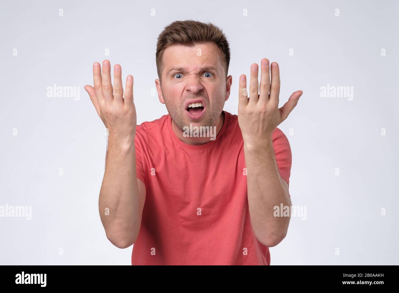 Wütender, wütender Mann mit mürrigem Grimace im Gesicht, mit aufgeregtem Mund, bereit zu argumentieren. Studio gedreht Stockfoto