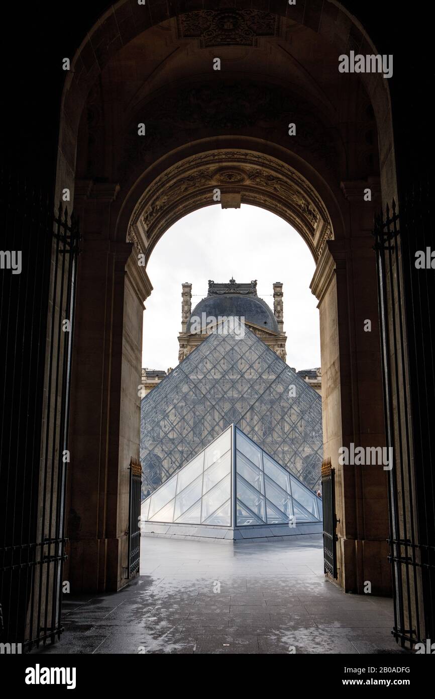 Die berühmten Pyramiden des Louvre, die durch einen Bogen in Paris gesehen werden. Stockfoto